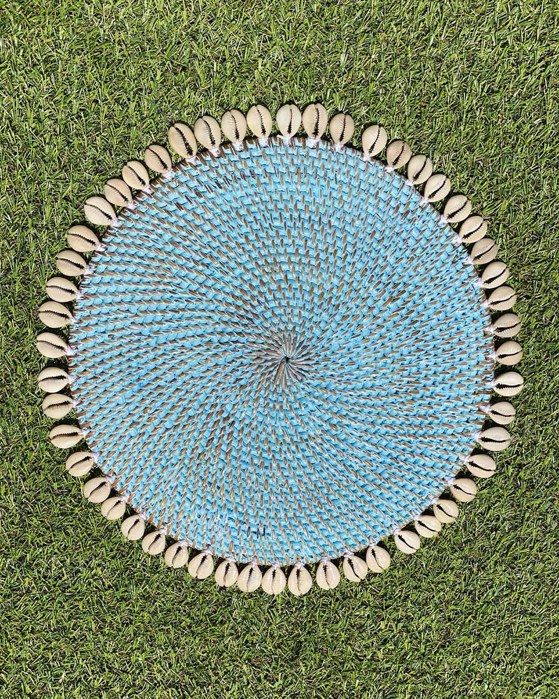 Table placemat in coloured aqua rattan edged with sea shells.