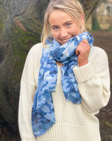 Woman wearing two blue camo scarf outside.
