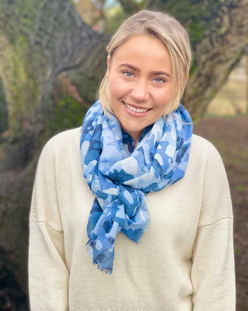Woman wearing two blue camo scarf outside.