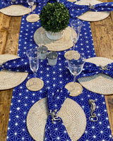 Table setting featuring white rattan placemats and blue geometric table runner.