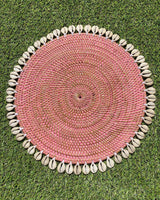 Table placemat in coloured pink rattan edged with sea shells.