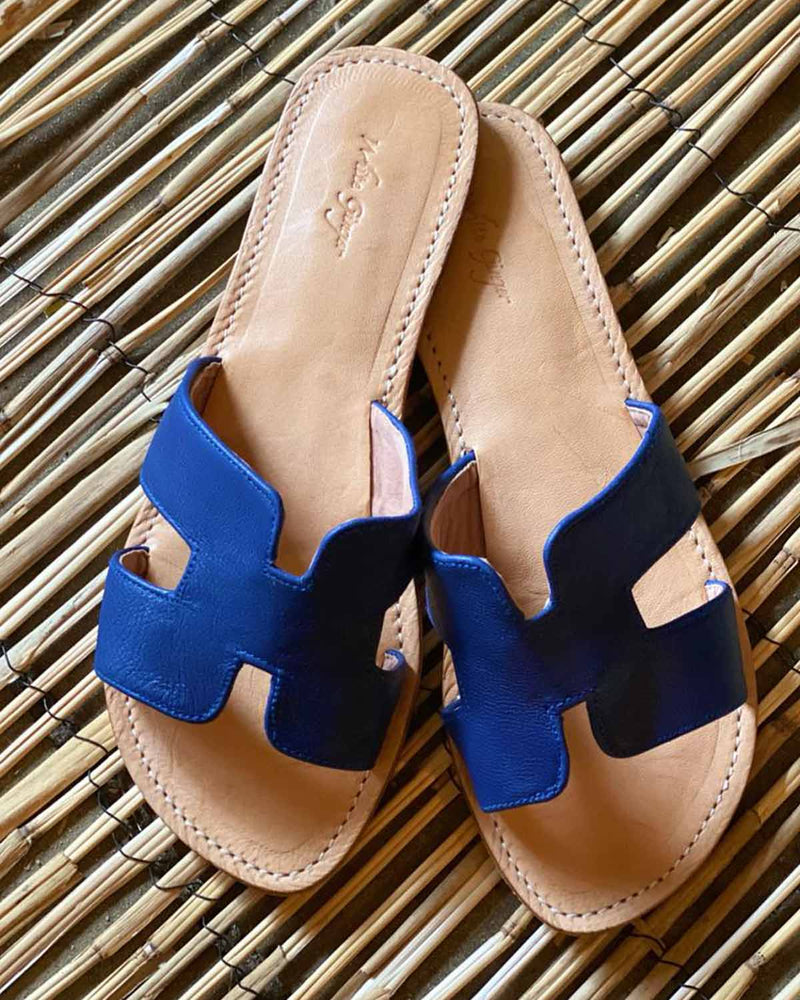 Woman in her fashion accessory, navy sliders made from 100% leather. The style is in a H design.